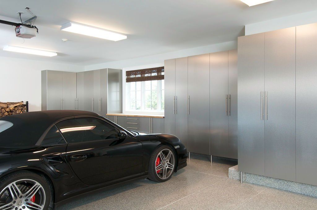 Black sports car parked in a clean garage with metallic storage cabinets.