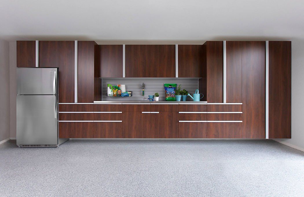 Brown kitchen cabinets with stainless steel refrigerator and gray speckled floor.