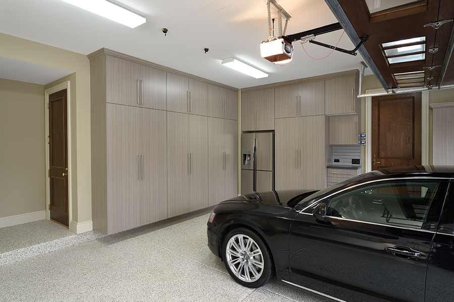 Garage with black car, light wood cabinets, and epoxy floor.