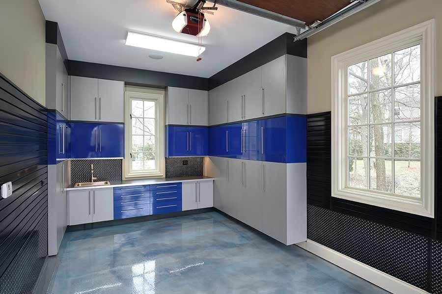 Garage interior with blue and gray cabinets, a window, and a shiny blue floor.