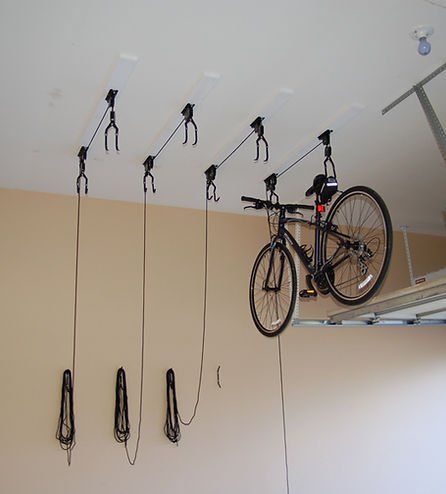 Black bicycle suspended from ceiling-mounted storage system in a garage.
