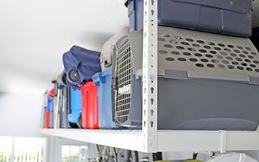 Overhead metal shelf holding various plastic storage containers in a room.