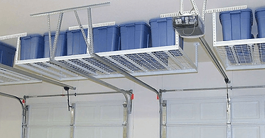 Overhead garage storage shelves with blue bins above closed garage doors.