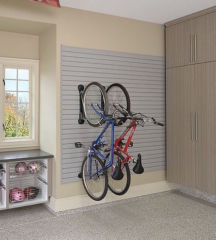 Garage with gray slat wall and hanging bicycles; tan cabinets and window on the left.