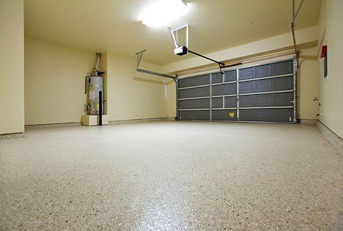 Empty garage with a gray epoxy floor, closed garage door, and water heater.