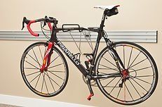 Black Pinarello road bike mounted on a wall bracket with red accents and a white saddle.