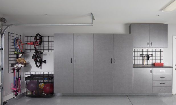 Garage with gray storage cabinets and wire shelving. Bicycle, toys, and garage door are visible.