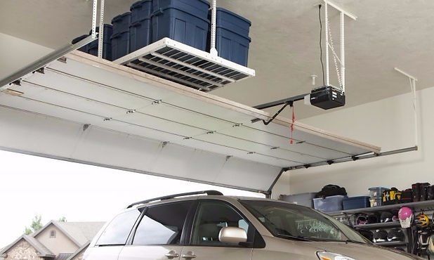 Overhead garage storage shelf holding plastic bins above a car.