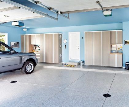 A gray SUV parked in a well-organized garage with cabinets, blue walls, and a white door.
