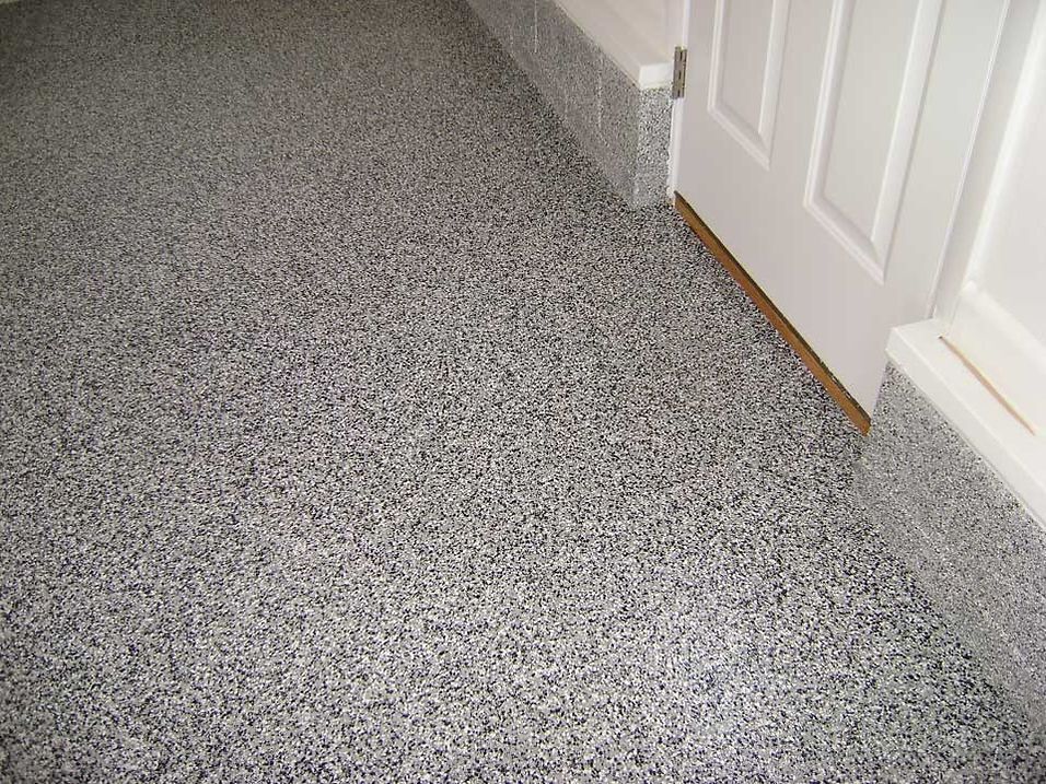Gray speckled epoxy floor next to a white door frame and baseboards.