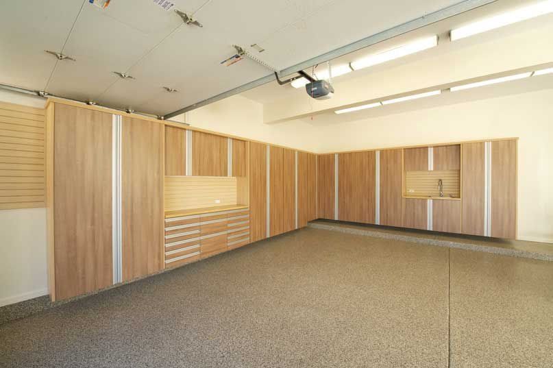 Garage with wooden storage cabinets and a speckled floor.