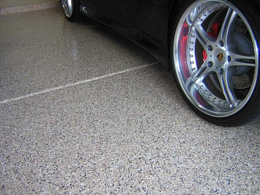 Black car parked on a speckled gray garage floor; chrome wheel visible.