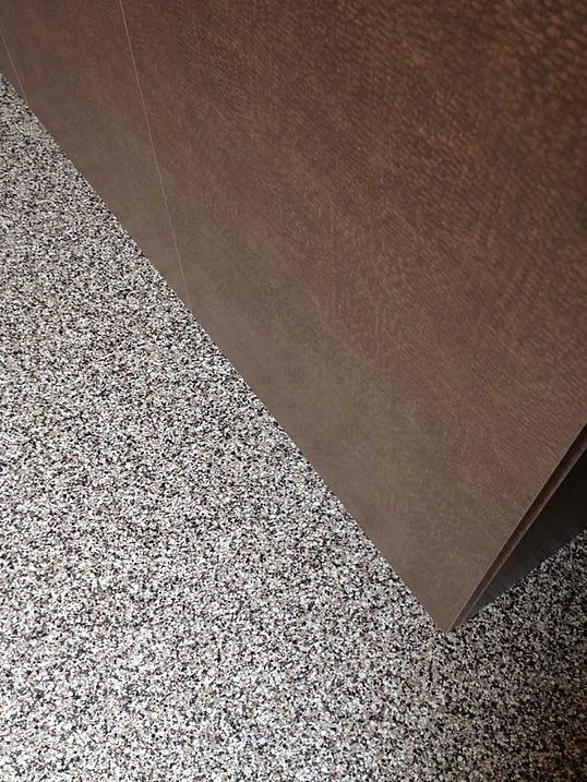 Brown wall paneling against speckled carpet flooring.