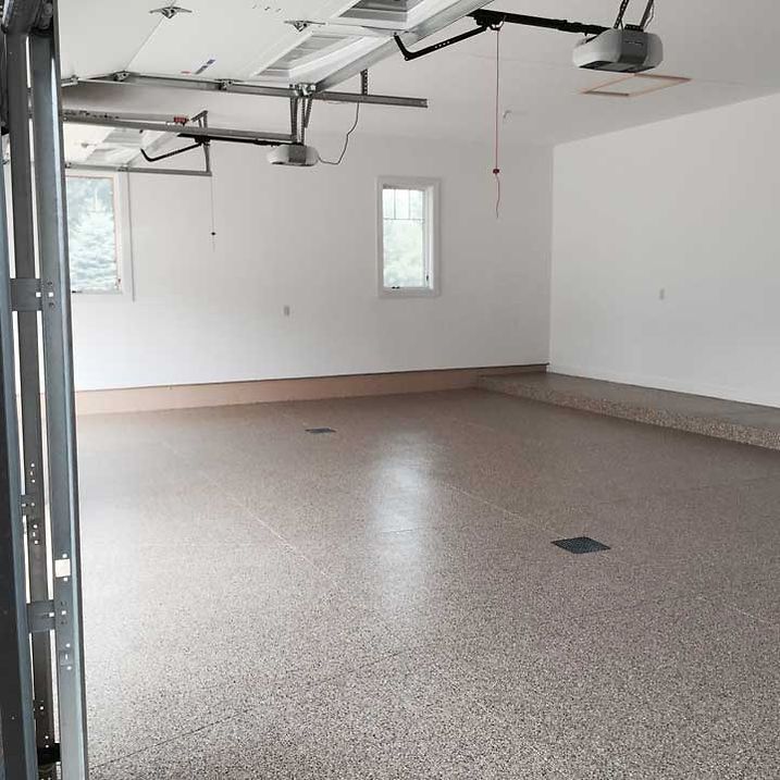 Empty garage with epoxy floor, white walls, and two overhead garage doors.