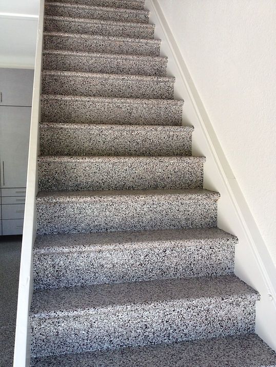Staircase with speckled gray steps, white trim and wall, leading upwards.