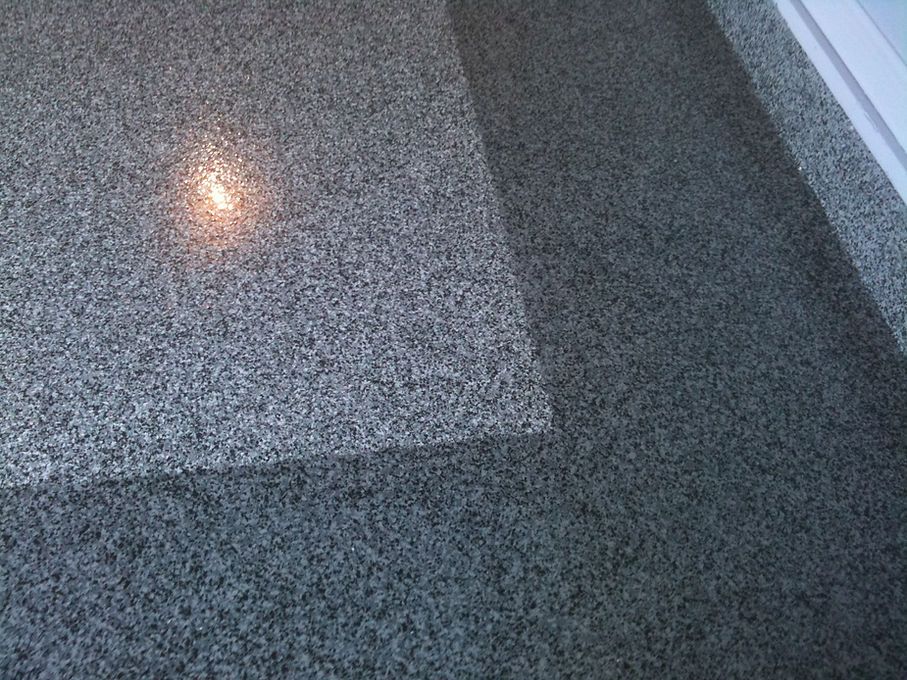 Gray speckled granite floor, with light reflecting on the polished surface, creating shadows.