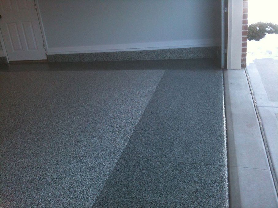 Garage floor with a speckled epoxy coating, partly shaded, leading to the open doorway.
