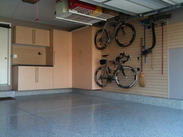 Garage interior with cabinets, two bikes hanging, and a shiny gray floor.