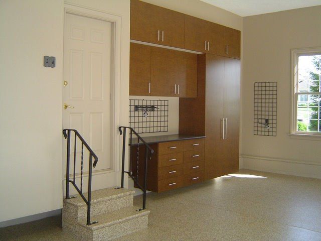 Garage interior with storage cabinets, drawers, door, and small staircase.