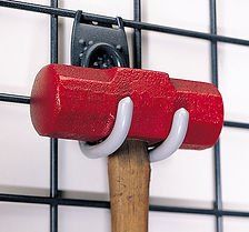 Red sledgehammer hanging on a grid wall using a tool holder.