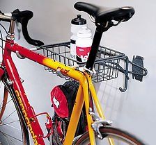 Red and yellow Cannondale bike on wall-mounted storage rack with basket, water bottles, and hooks.