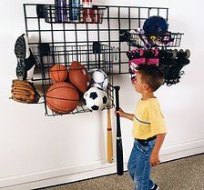 Boy by organized wall storage of sports equipment.