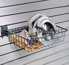 Wire basket on a slotted wall holding a circular saw and wood pieces.