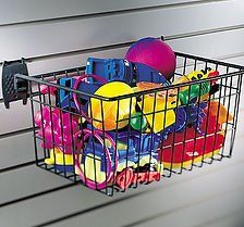 Black wire basket holding colorful toys, hanging on a slat wall.