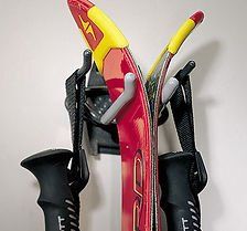 Black wall-mounted ski rack holding red and yellow skis with black poles.