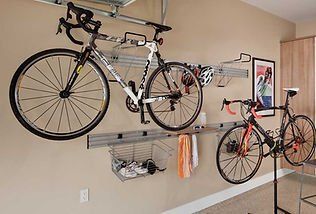 Bicycles stored on a wall-mounted rack in a garage. Accessories are stored in baskets below the bikes.