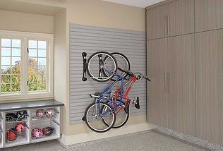 Garage with a grey slat wall holding two bicycles. A cabinet and window are also in the space.