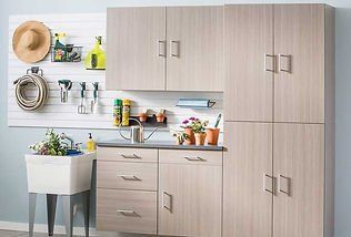 A utility room with cabinets, a sink, and pegboard for storage, with gardening supplies.