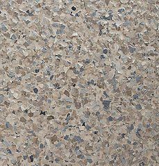 Close-up view of a speckled floor coating, primarily beige, gray, and blue flakes.