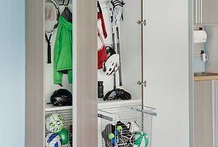 A closet organized with jackets, sports equipment, and balls. White doors open to reveal items inside.