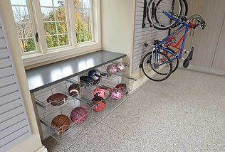Garage with sports equipment storage: ball bins, bike rack, window, and gray bench.