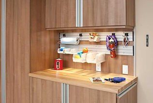 Wooden garage workspace with cabinets, countertop, and hanging storage.