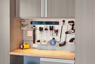 Workbench with tools hanging on a pegboard, including a level, screwdrivers, and a drill.