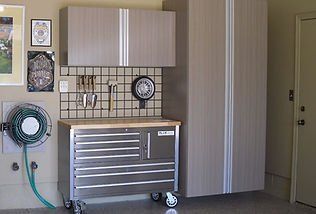 Garage organization system with cabinets, workbench, and tools.