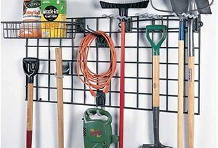 Black metal grid wall organizer with gardening tools and supplies.