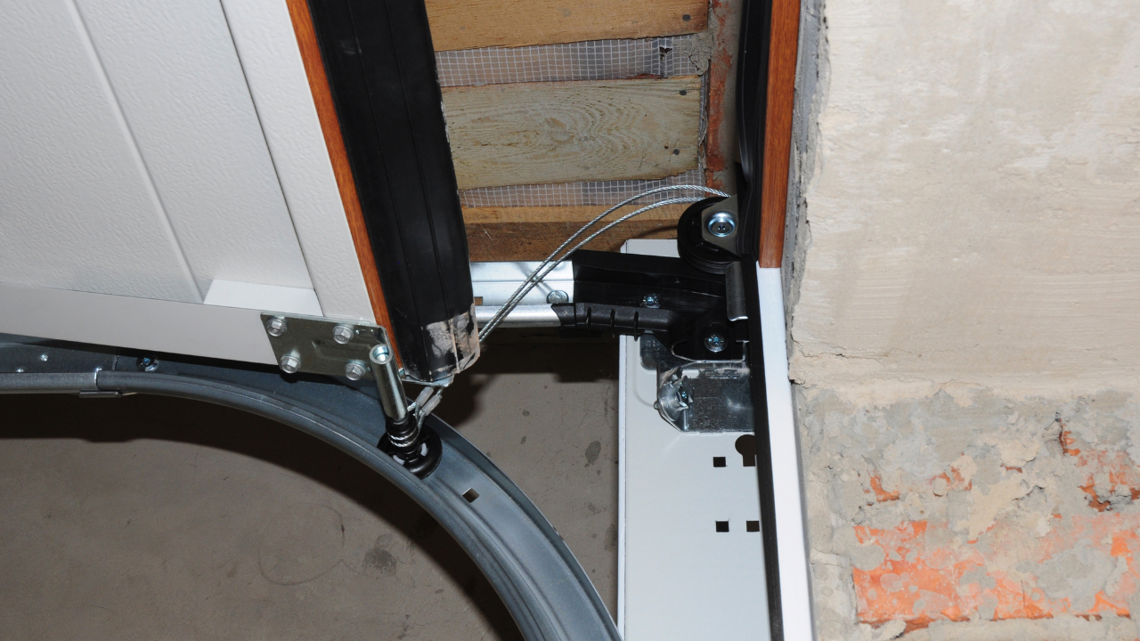 Garage door mechanism with curved track, black hardware, and white panels.