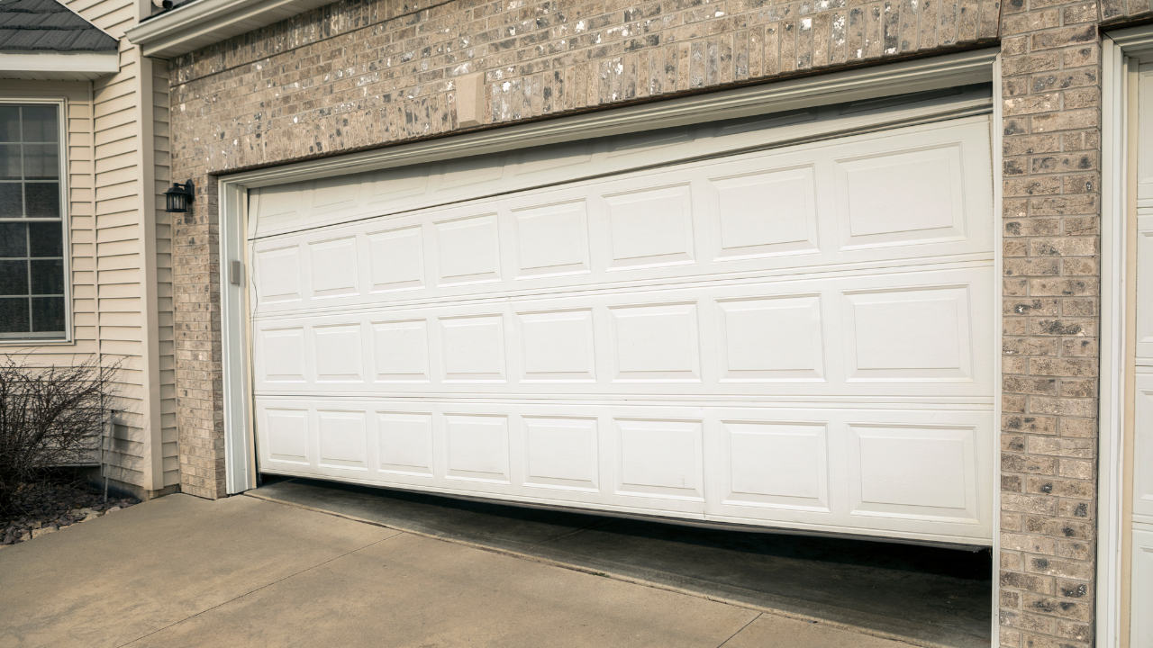 White garage door partially open on a brick house.