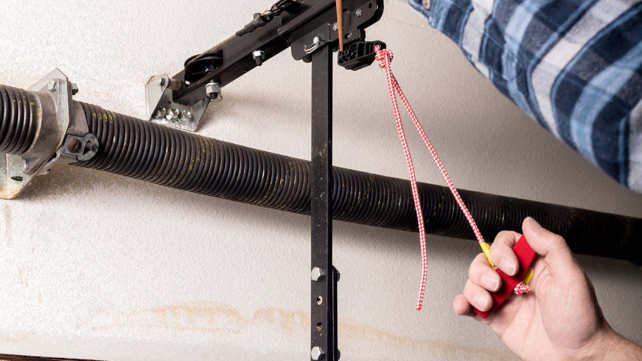 Person pulls a red emergency release cord on a garage door system.