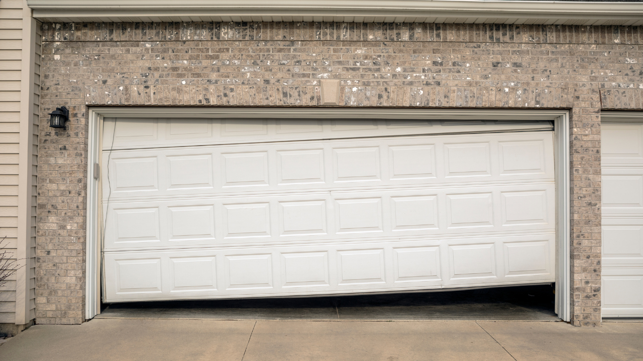 Garage door partially open, slanted. Brick and siding exterior.