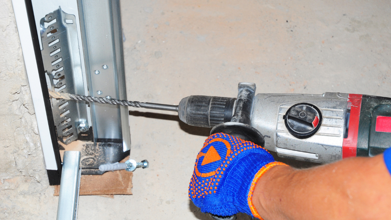 Person using a drill to install hardware on a garage door track.