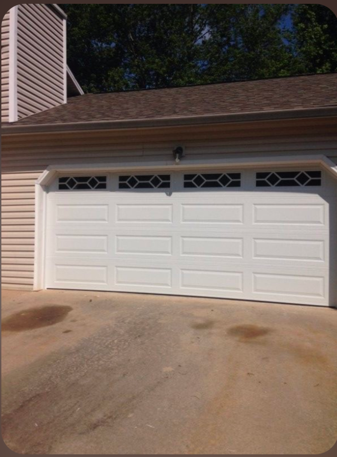 White two-car garage door with decorative windows in a residential driveway