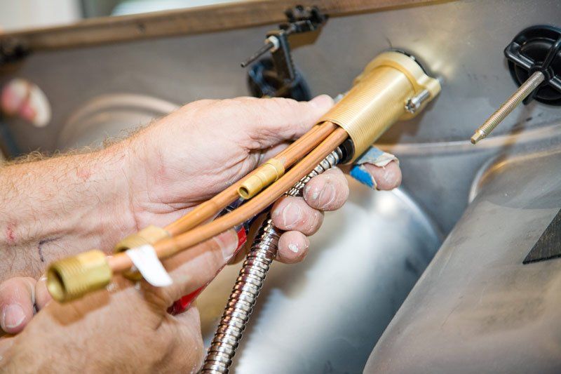 Plumbers Hands Installing A Faucet In A Sink — Dempsey Plumbing in Long Jetty