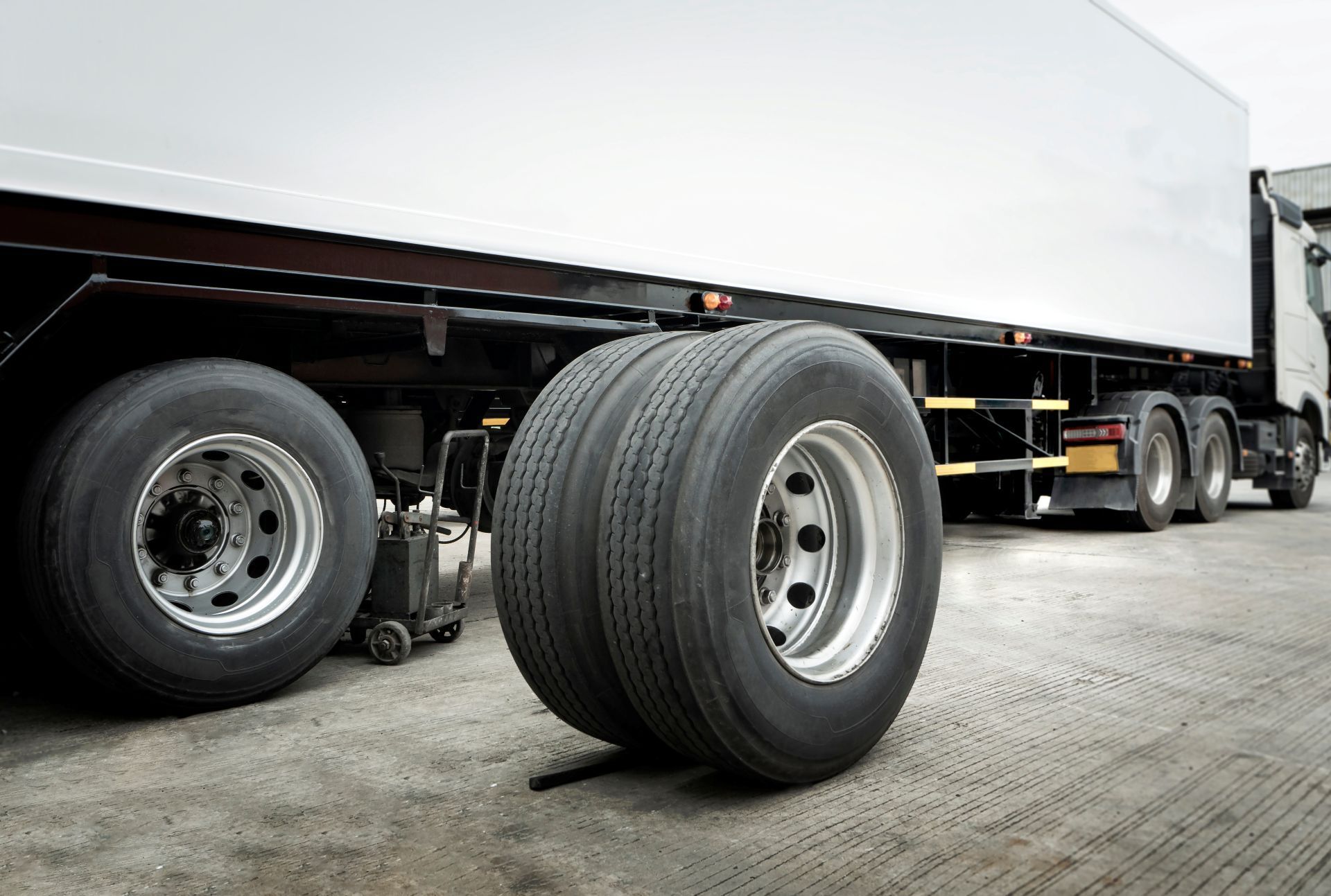 Low-angle view of a semi-truck trailer with large black tires on a paved surface