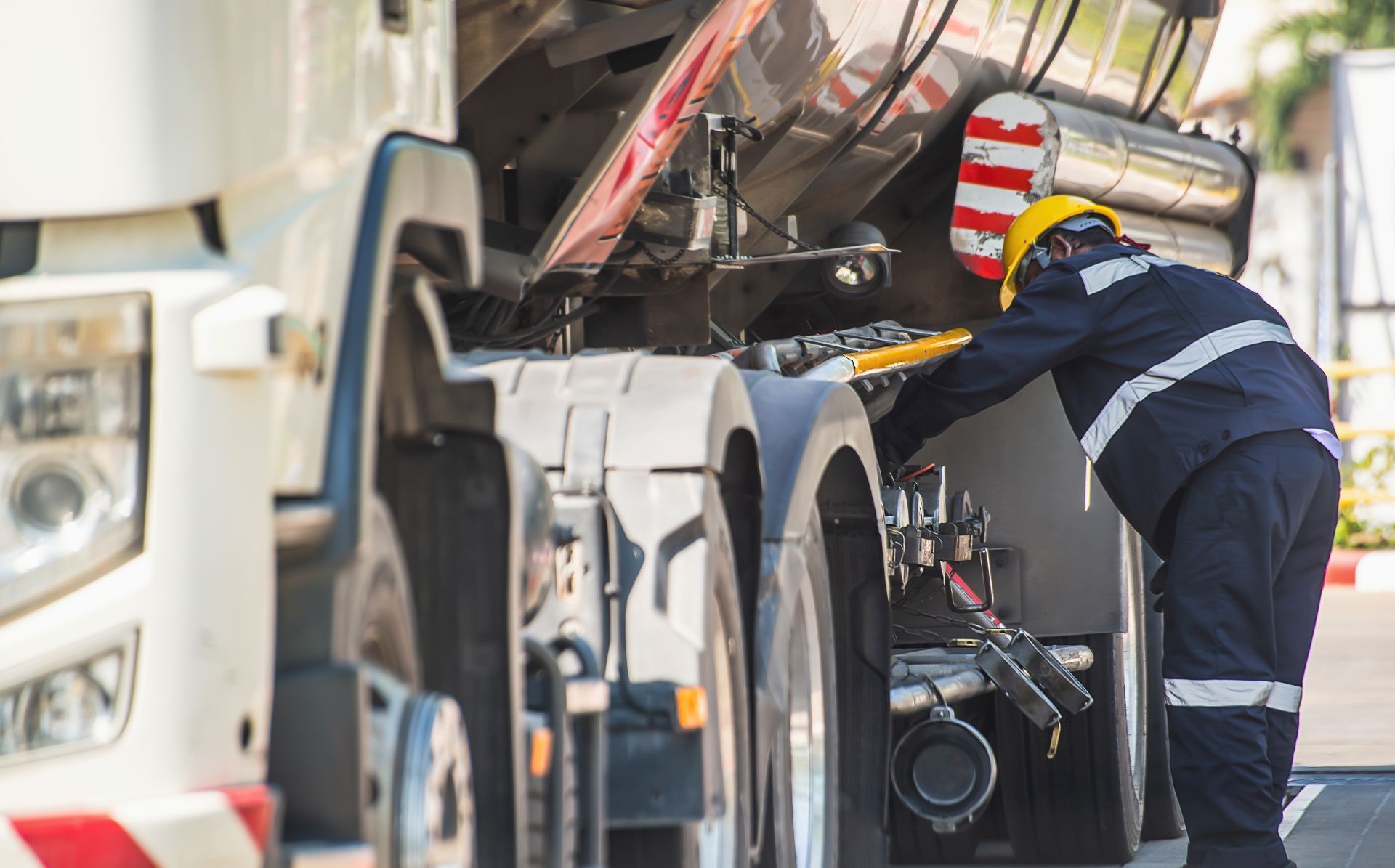 Worker in hard hat inspecting a large truck or industrial vehicle at a construction site