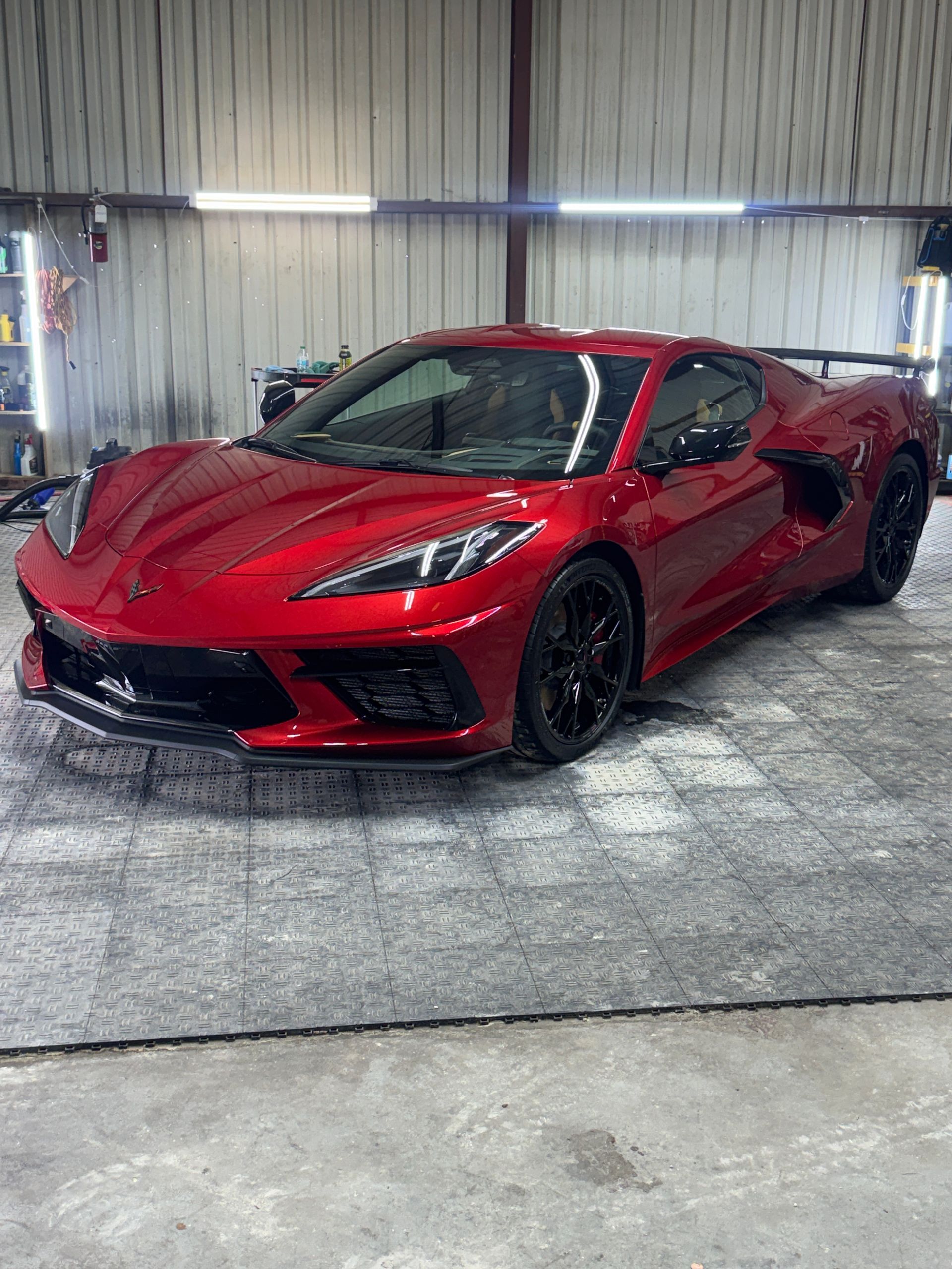 Red sports car in a garage with bright overhead lights.