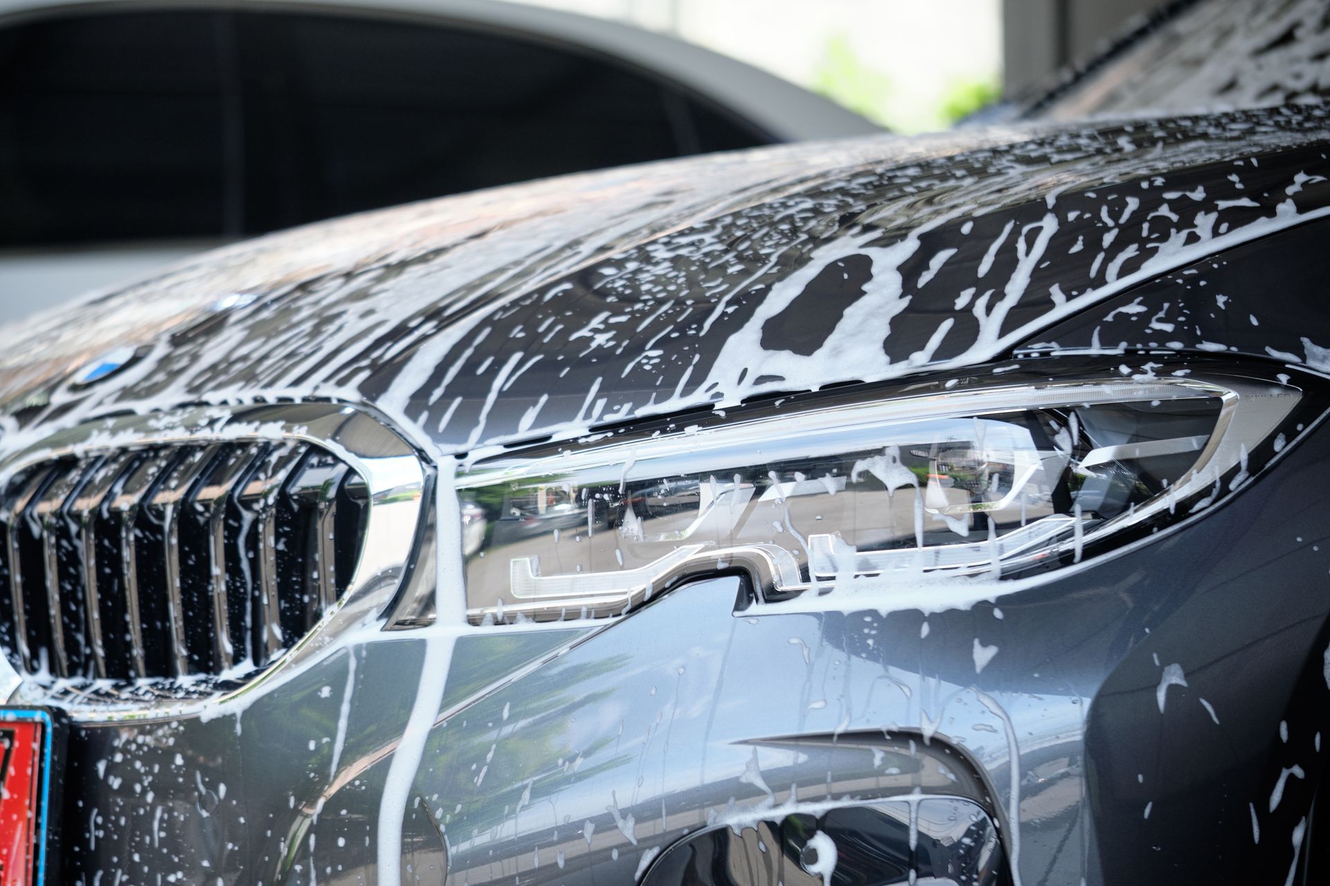 Gray BMW being washed with foamy soap.